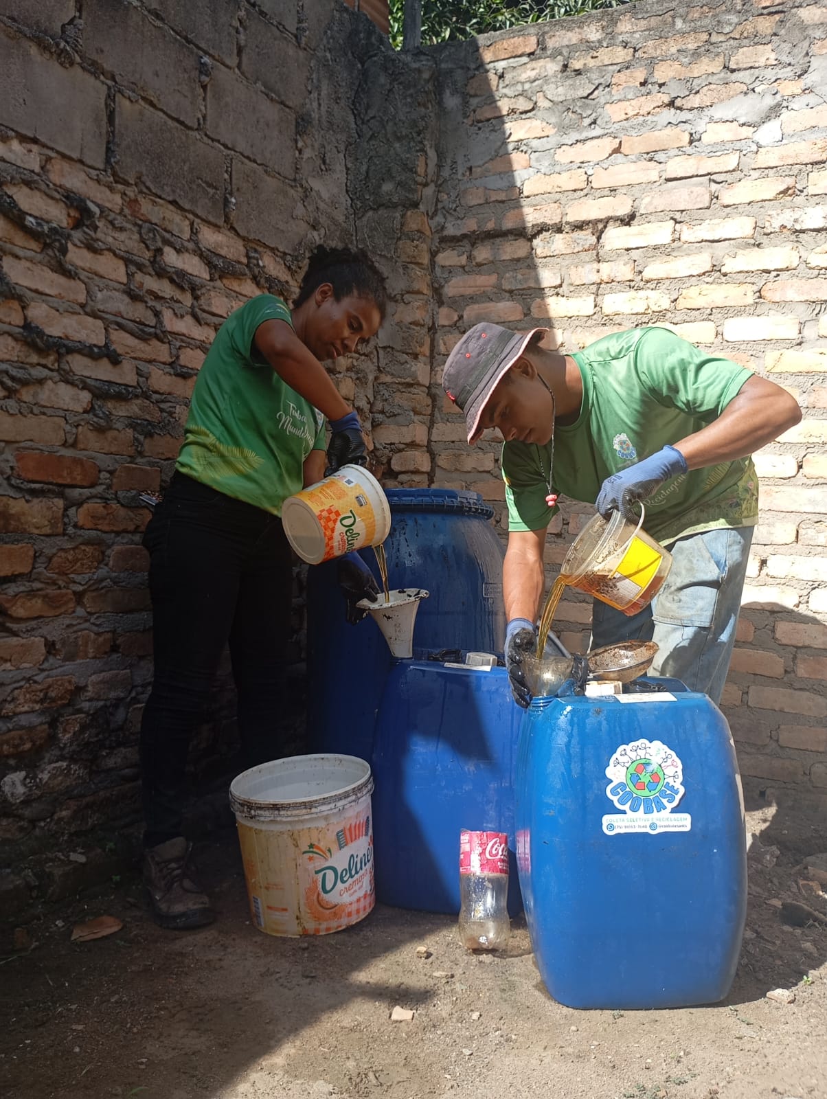 Catadores transferindo óleo usado para recipientes de coleta